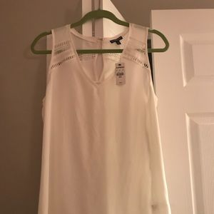 Sleeveless, cream colored delicate blouse.